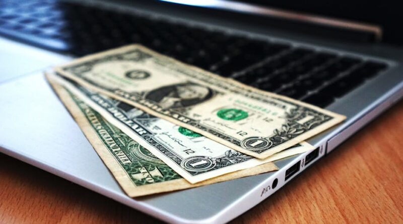 Close-up of US dollar bills placed on a laptop symbolizing digital finance and economy.